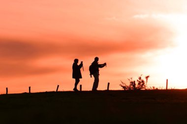 people taking photos in the meadow, sunset in spring season 