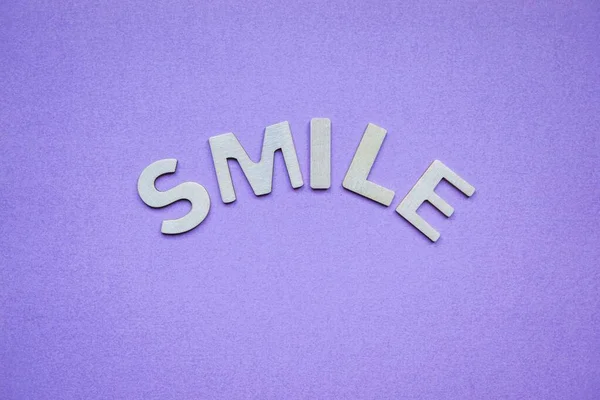 紫色の背景に木の文字で笑顔の言葉 — ストック写真
