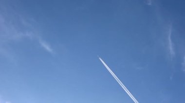 Gökyüzünde yükseklerde uçan jet uçağı açık mavi gökyüzünde kontrastlar bırakır.