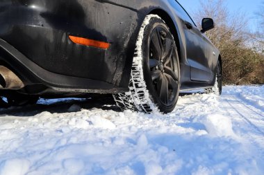 Güneşli bir günde Almanya 'da bir kış manzarasının önündeki siyah Ford Mustand spor arabası