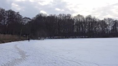 Donmuş bir gölde buz pateni yaparken kadın ayaklarına yakın dur.