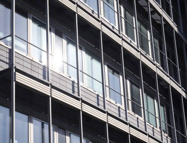 Almanya 'da Kiel' de bulunan pencerelere cam ve güneş ışığı yansıtan modern ofis cepheleri.