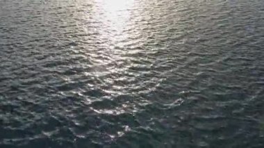 Dalgalar, dalgalar ve güneş ışığı yüzeye yansıyan su yüzeyinin detaylı yakın görüntüsü