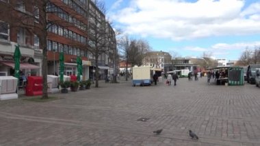 Güneşli bir günde Almanya 'nın Neumunster şehrinde pazar tezgahları ve Covid-19 sırasında insanların bulunduğu pazar yeri.