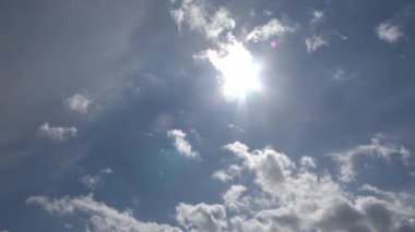 Parlak güneş ışınlarının güzel manzarası, mavi gökyüzünde parlayan mercekler ve bulutlar.