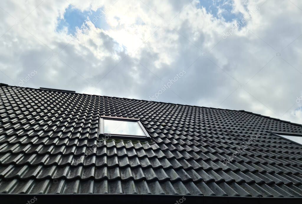 Open roof window in velux style with surrounding black roof tiles