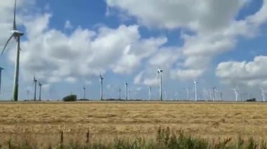 Almanya 'da temiz enerji üreten büyük bir yel değirmeni parkı boyunca giden bir arabanın yan görüntüsü