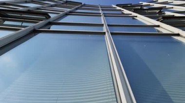 Modern ofis yüzleri cam ve yansıtan güneş ışığı ve bazı bulutlar ile.