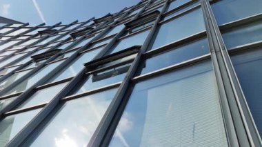 Modern ofis yüzleri cam ve yansıtan güneş ışığı ve bazı bulutlar ile.