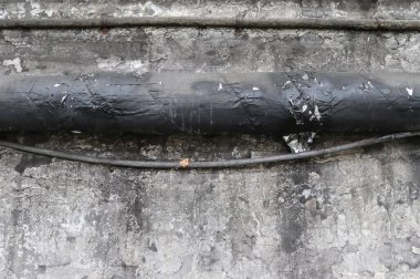 Çelik fabrikasının duvarında açık kullanım izleri, çatlaklar ve borular var. Yüksek çözünürlüklü arka plan