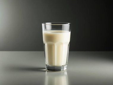 Refreshing glass of milk sits on a reflective surface against a dark backdrop, creating a simple yet elegant image