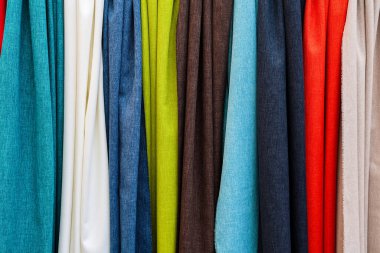 Perakende veya tasarım ortamında çok çeşitli malzeme ve renk seçenekleri sunan canlı tekstil örnekleri