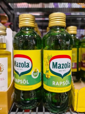 Kiel, Almanya - 10. Kasım 2025: Perakende satış rafında sarı etiketli Mazola Rapsoel şişeleri, pişirme yağı çeşitliliği ve sağlıklı gıda seçeneklerini temsil ediyor