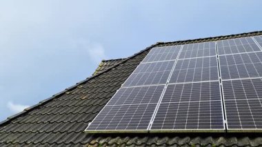 Modern fotovoltaik modüller fayanslı bir çatıya kurulmuş. Temiz mavi gökyüzüne karşı güneşten yenilenebilir, sürdürülebilir enerji üretiyor. Çevresel koruma ve yeşil enerjiyi destekliyor.