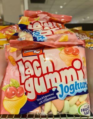 Kiel, Germany - 24. November 2025: Stacked colorful Lachgummi Joghurt fruit gummy bags with vitamins on supermarket shelf, bright retail packaging assortment