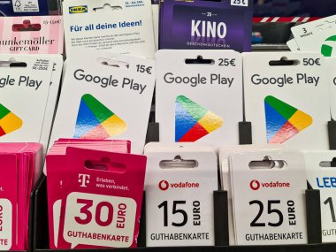 Kiel, Almanya - 24. Kasım 2025: Google Play, IKEA, Vodafone ve T-Mobile gibi popüler markalar için çeşitli hediye kartları bir perakende mağazasında sergilenerek ödeme ve hediye çözümleri sunuldu