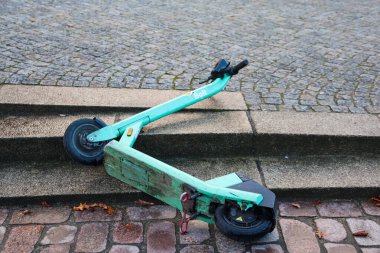 Kiel, Almanya - 13. Aralık 2025: Kamu merdivenlerinde kırılmış halde yatan sürgülü elektrikli scooter, kentsel atık sorununu gösteriyor