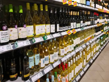 Kiel, Almanya - 13. Aralık 2025: Bir Alman süpermarketinde raflarda fiyatlar ve yeni etiketlerle birlikte beyaz ve kırmızı şarap şişeleri