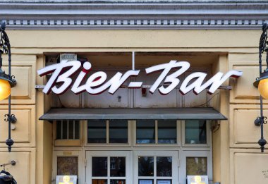 Flensburg, Almanya - 20. Aralık 2025: Dekoratif lambalı bir bar girişinin üzerinde ışıklı Bier-Bar tabelası