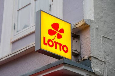 Flensburg, Almanya - 20. Aralık 2025: Eski bir bina duvarında kırmızı yonca yaprağı logosu gösteren aydınlatma işareti