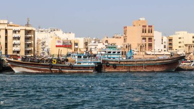 Dubai, Arap Emirlikleri - 26. Eylül 2025: Dubai Deresi boyunca arka planda tarihi bölge binaları bulunan ahşap dalışı