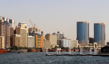 Dubai, Arap Emirlikleri - 26. Eylül 2025: Dubai Creek limanı kentsel ufuk çizgisini, geleneksel tekneleri ve ticari binaları gösteriyor