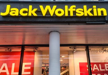 Kiel, Almanya - 07. Ocak 2026: Jack Wolfskin perakende mağazasında önde gelen sarı bir logo ve kırmızı satış afişleri yer alıyor