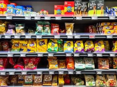 Kiel, Almanya - 07. Ocak 2026: Süpermarket rafları çok çeşitli paketlenmiş abur cubur ürünleri ve fiyat etiketlerini gösteriyor