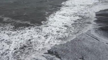Karanlık bir okyanustan gelen güçlü dalgalar İzlanda 'daki volkanik siyah kum plajını kaplıyor.