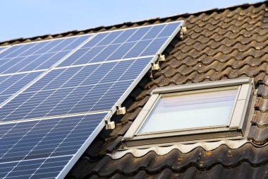 Güneş panelleri ve çatı penceresi kiremitli çatıda. Güneş enerjisini yakalıyor.