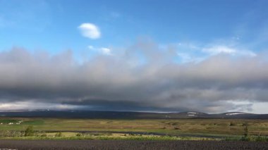 İzlanda dağlarındaki geniş yeşil ve volkanik bir arazide hareket eden yuvarlanan bulutlar.