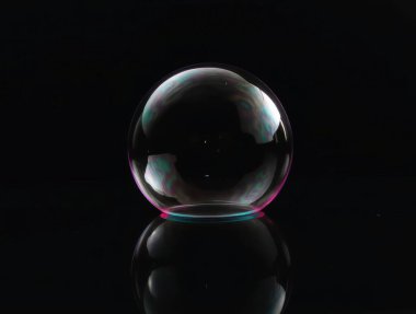 Sabun köpüğünde ışık kırılması siyah yansıtıcı yüzeyde renkli girdaplar yaratıyor.