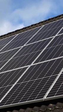 Bulutlar mavi gökyüzünde hareket ederken çatıdaki güneş panelleri temiz enerji üretiyor.