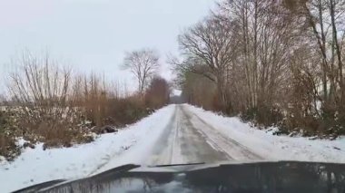 Uzak bir kırsal alanda kaygan ve karlı bir yolda araba sürerken ilk kişi görüntüsü