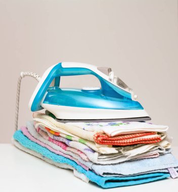 Ütü, ütülenmiş çarşafların yanında. Konsept - ev işleri.