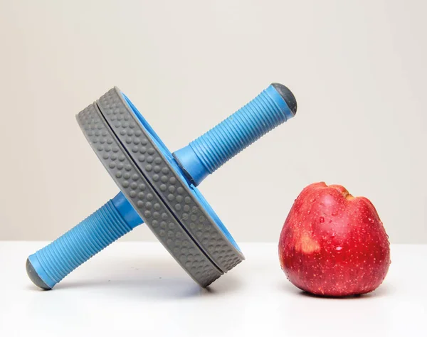 a press roller on a white background with an apple lying on the press roller. Sports and healthy eating