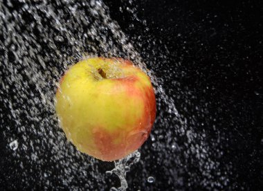 Siyah arka planda, suyun altında kırmızı bir elma. Kavram-meyve diyeti