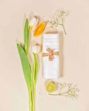 Beyaz havlu, lale ve narenciye arkaplanlı çevre dostu spa kompozisyonu. Rahatlama prosedürü, spa tedavisi, masaj hazırlığı. Üst görünüm