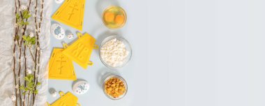 Avuç içi. Ortodoks Paskalyası için hazırlık. Paskalya pastası yapmak ve yumurtaları palmiye dallarıyla süslemek için mavi arka planda fotokopi alanı ile süsleyen Holliday yatay afişi. Düz yatıyordu