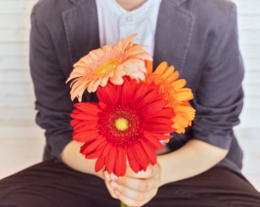 Elinde bir buket renkli gerbera olan bir okul çocuğuyla bulanık bir kompozisyon. Okul yılının sonu ya da başlangıcı kavramı ve öğretmene minnettarlık. İlk lise aşkı