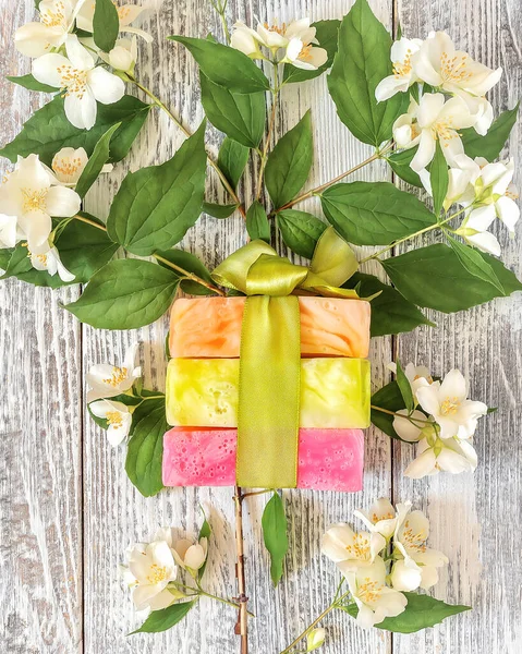 Barre di fiori naturali fatti a mano e sapone alle erbe o shampoo secco su un ramo di gelsomino in fiore — Foto Stock