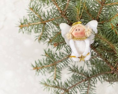 Noel ağacında sevimli bir Noel meleği oyuncağı ve bulanık bir arka plan.