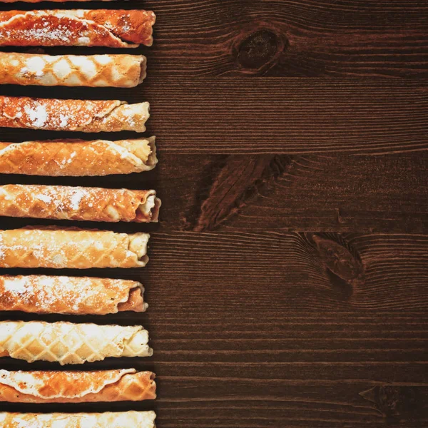 Odaklanma yok, üzerinde tatlı waffle tüpleri olan yemek afişi fotokopi alanı olan ahşap bir arka plan. Lezzetli, ev yapımı hamur işi, gofret tüpleri. Tatil için tatlı atıştırmalıklar. Düz yatıyordu