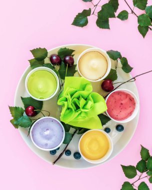 Sütsüz, meyveli dondurma veya donmuş yoğurt. Çeşitli ev yapımı, vejetaryen, meyveli dondurma, yapraklar, böğürtlen ve pembe arka planda kirazlı yaz yemeği kompozisyonu. Yaz tatili yemekleri