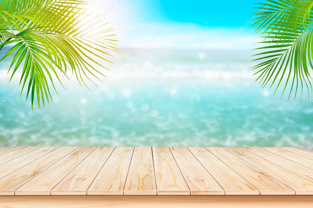 Empty brown wooden table. Blur beautiful nature green palm leaf on tropical beach with bokeh background of abstract  ,can be used for montage or display your products