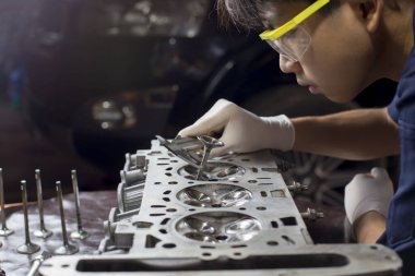 Otomobil tamircisi garajda çalışıyor. Tamir servisi. Otomobil motoru silindiri, bakım onarımı için otomobil servis istasyonunda açılır. 