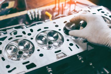 Otomobil tamircisi garajda çalışıyor. Tamir servisi. Otomobil motoru silindiri, bakım onarımı için otomobil servis istasyonunda açılır.