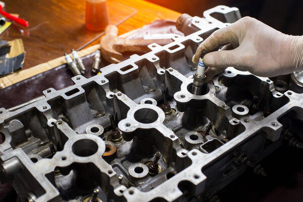 Auto mechanic working in garage. Repair service.  opened automobile engine cylinder head for maintenance repair at car service station for diagnosis