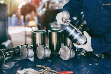 Otomobil tamircisi garajda çalışıyor. Tamir servisi. Bağlantı çubuğu, piston ve silindir bloğu parçalanmış durumda. Teşhis için servis istasyonunda bakım onarımı