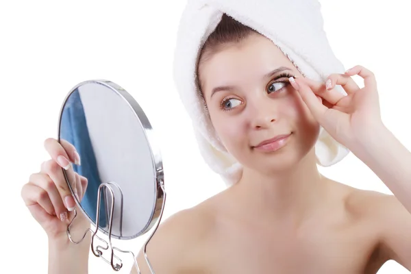 La fille dans une serviette après une douche, colle les cils regardant dans un miroir . — Photo